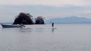Un lago tranquilo con una persona haciendo paddleboard y un barco pequeño anclado cerca.