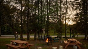 Un camping con mesas de picnic, una fogata y un banco.