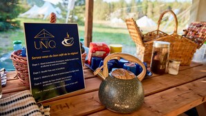 Una mesa de madera con un cartel que detalla un proceso de preparación de café en cinco pasos, una tetera de madera y diversos recipientes y utensilios.