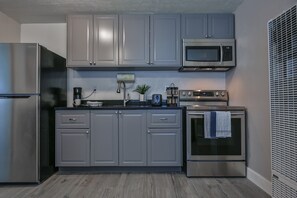 Una cocina moderna con gabinetes grises, electrodomésticos de acero inoxidable y un microondas empotrado.