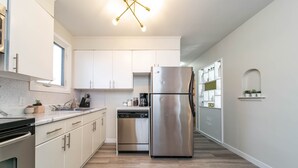 A modern kitchen with white cabinets, stainless steel appliances, and a wooden floor. - ★6B Modern Bungalow★King Bed/WiFi✔Long Stays★Clean (Edmonton)