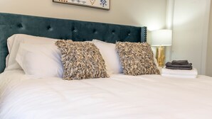 A neatly made bed with white linens and two decorative pillows, a dark green upholstered headboard, and a framed artwork above. - ★6B Modern Bungalow★King Bed/WiFi✔Long Stays★Clean (Edmonton)