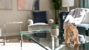 A modern living room with a glass coffee table, a small potted plant, and a paper mache elephant sculpture. - ★6B Modern Bungalow★King Bed/WiFi✔Long Stays★Clean (Edmonton)