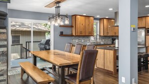 Una cocina moderna con armarios de madera, un comedor con mesa y sillas de madera, y una isla integrada con un lavamanos.
