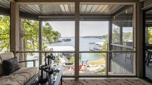 Habitación con grandes ventanales que dan a una masa de agua, un área de terraza y vistas a barcos y muelles.