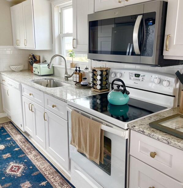Enjoy cooking in this well-equipped kitchen with a stainless steel range hood, microwave, and digital clock.
