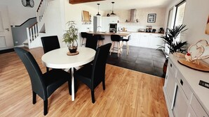 A modern kitchen with white cabinets, a dining area with a round table and black chairs, and a staircase leading to an upper floor. - ☀︎ Quiet house - 5min from Cognac - 1/8 pers ☀︎ (Cherves-Richemont)