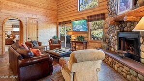 A cozy log cabin interior with a fireplace, comfortable seating, and a television. - Greer Riverside Getaway (Cabin 168) (Greer)