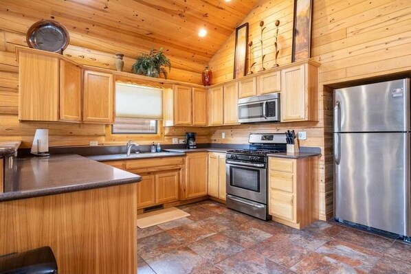 Enjoy cooking in this well-equipped kitchen with a central island, stainless steel appliances, and a tiled floor.