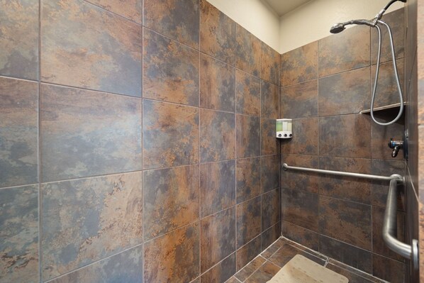 A shower area with brown tiles, a handheld showerhead, and a grab bar. - Greer Cowboy Lodge (Cabin 169) (Greer)