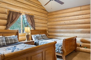 Two plush beds with headboards and footboards, adorned with plaid bedding and pillows, are situated in this charming bedroom.