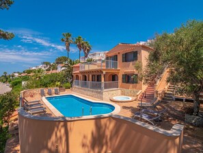 A Mediterranean-style villa with a swimming pool, outdoor seating, and a staircase leading to a balcony. - 5 bedroom villa with stunning sea views (San Jaime Mediterráneo)