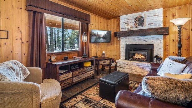 A cozy cabin interior with a fireplace, wooden walls, a television, and a comfortable seating area. - Cowboy Casita (Cabin 102) (Greer)