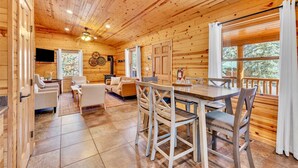 A wooden cabin interior with a dining area, sofa, and a fireplace. - Monteverde Retreat (Cabin 104) (Greer)