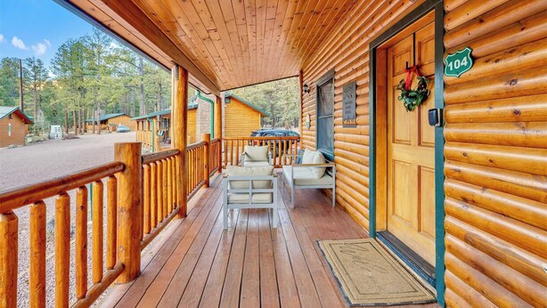A wooden cabin with a porch, a welcome sign, and a number sign. - Monteverde Retreat (Cabin 104) (Greer)
