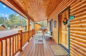 Une cabane en bois avec un porche, une pancarte de bienvenue et un panneau indiquant le numéro de la cabane.
