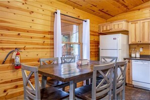 Cozy cabin interior with a dining area, kitchenette, and rustic charm.