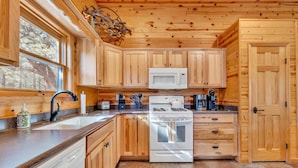 A kitchen with wooden cabinets, a microwave, a stove, and a sink. - Monteverde Retreat (Cabin 104) (Greer)