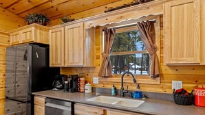 A wooden cabin kitchen with a refrigerator, coffee maker, sink, and cabinets. - Black Bear Chalet (Cabin 105) (Greer)