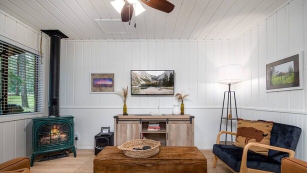 A cozy living room with a green wood-burning stove, a blue sofa, and a wooden coffee table. - Aspen Cabin 1 (Greer)