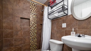 A bathroom with a toilet, sink, shower, and a towel rack. - Aspen Cabin 2 (Greer)