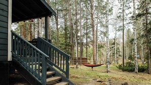 A wooden cabin with a porch and staircase, surrounded by tall trees. - Cowgirl Cabin (Aspen 3) (Greer)