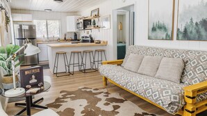 A cozy living room with a patterned sofa, a wooden coffee table, and a cowhide rug. - Cowgirl Cabin (Aspen 3) (Greer)