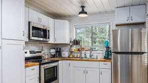 Et moderne køkken med hvide skabe, rustfrie stålapparater og en træbordplade.