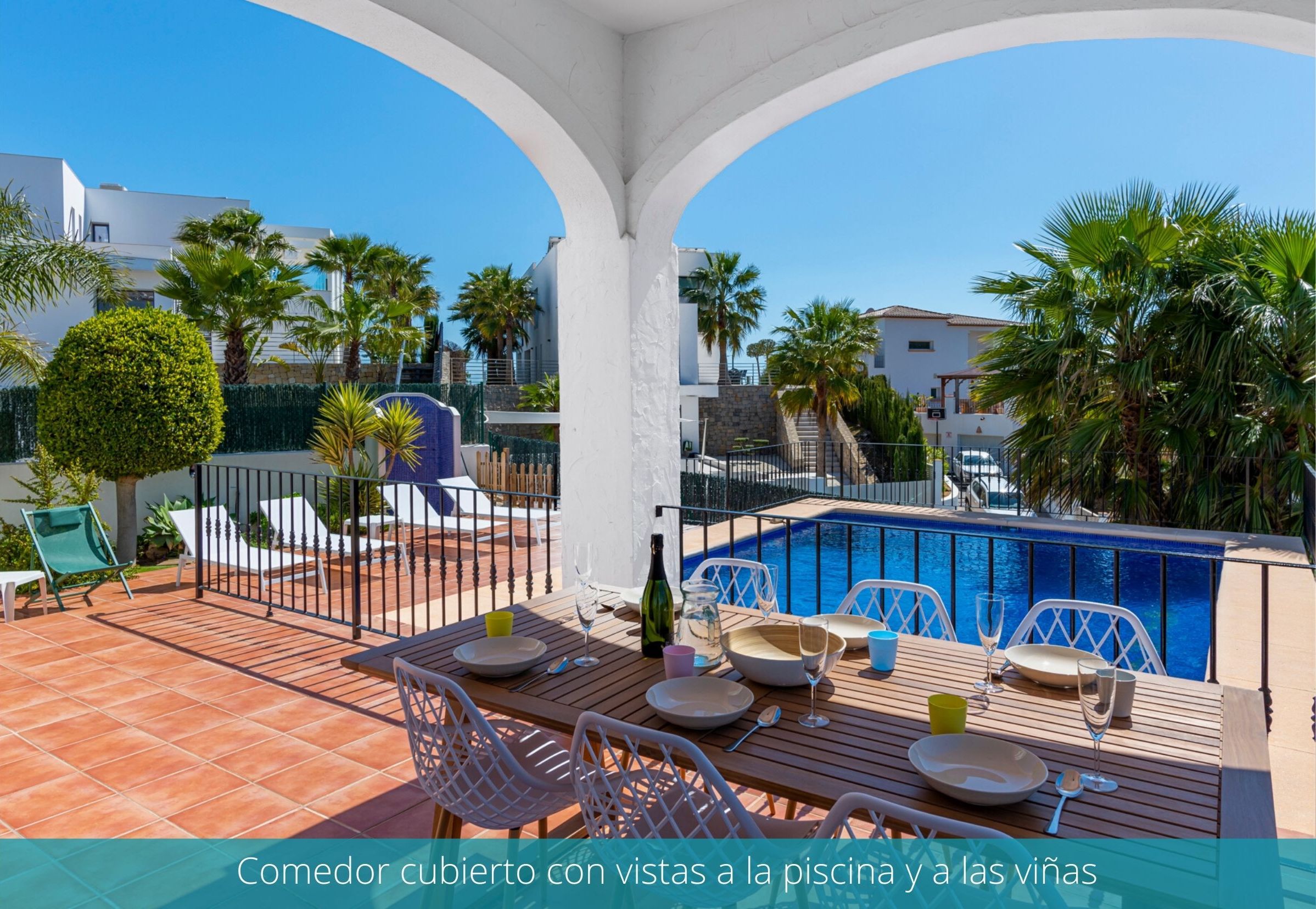 A covered outdoor dining area with a view of a swimming pool and villas.