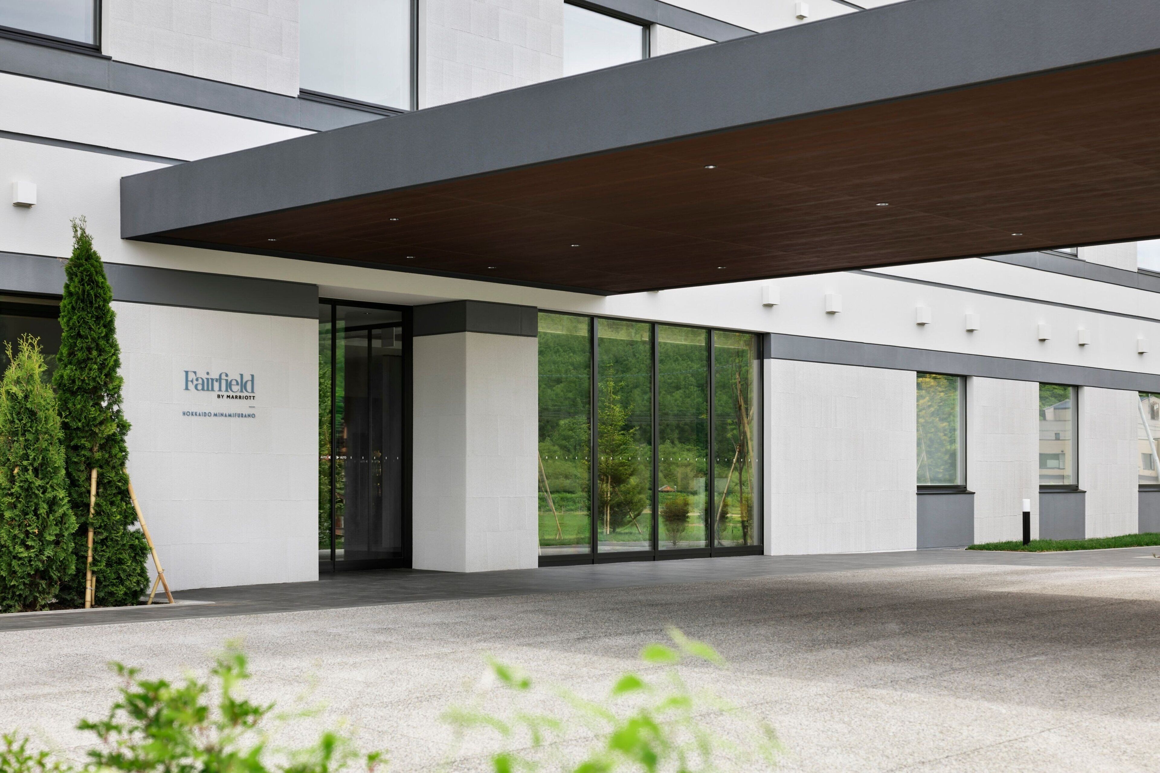 A modern building entrance with a large glass facade, a wooden overhang, and a sign reading "Fairfield."