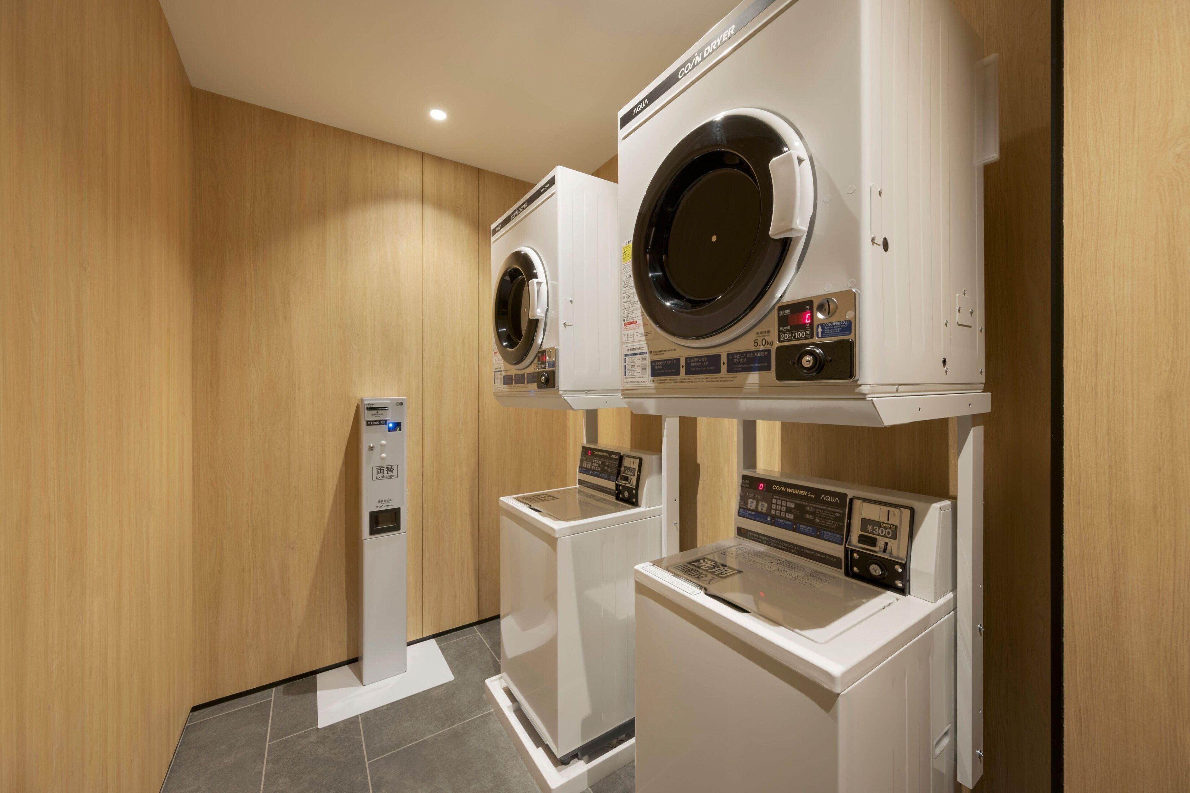 A laundry room with two front-loading washing machines and a coin-operated dryer.