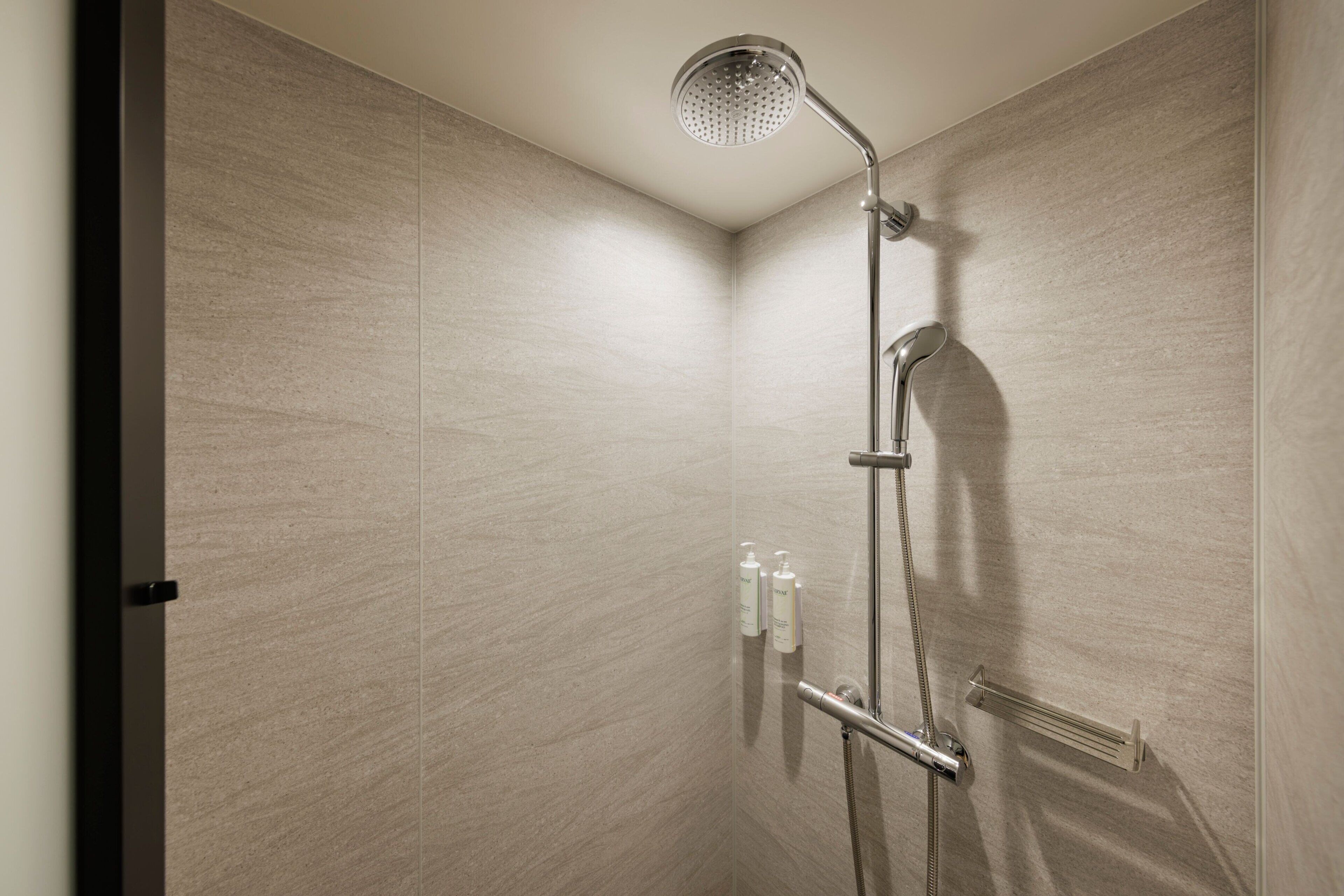 A modern shower with a handheld showerhead and a wall-mounted faucet.