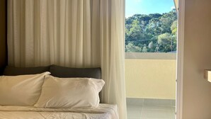 A bedroom with a bed, curtains, and a view of a balcony. - GOLDEN GRAMADO RESORT LAGHETTO (Gramado)
