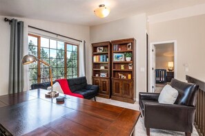 A spacious room with a large wooden dining table, two leather sofas, and a bookshelf filled with books and decorative items.