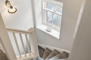 Un escalier avec une rampe blanche menant à un palier doté d’une fenêtre en verre dépoli.