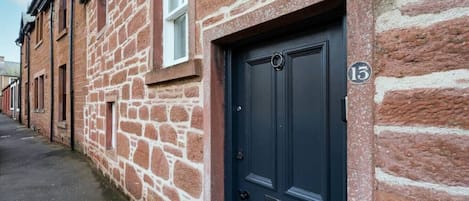A stone building with a dark blue door and a small window.
