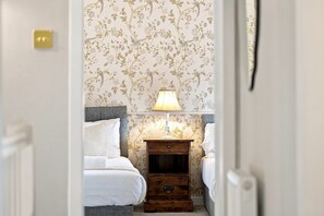 Une chambre à coucher avec un lit, une table de chevet, une lampe et un papier peint à motifs floraux.
