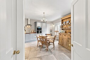 Une cuisine avec une table à manger et des chaises, un lustre et des placards.