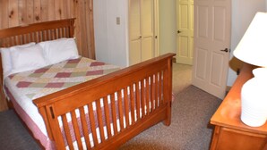A bedroom with a wooden bed, a nightstand, and a door leading to another room.