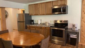 A modern kitchen with wooden cabinets, stainless steel appliances, and a round dining table with chairs.