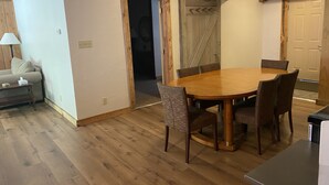 A dining area with a wooden table and chairs, a sofa, and a lamp.