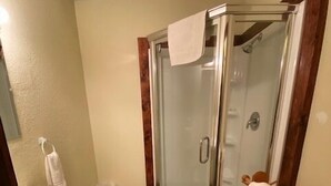 Un baño con ducha de vidrio, lavamanos y perchero para toallas.