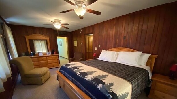 Un dormitorio con una cama de madera, una silla, un aparador y un ventilador de techo.