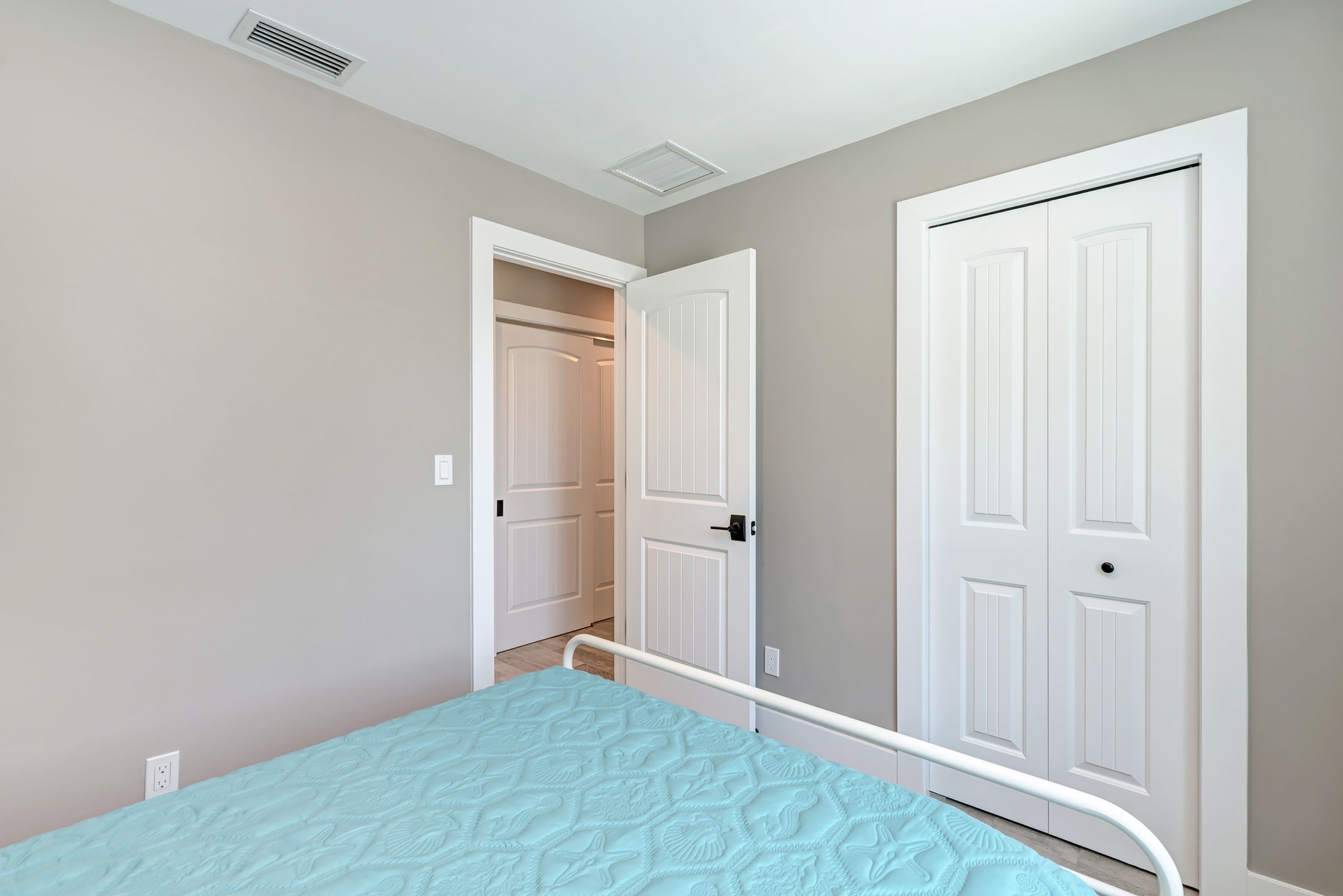 Un dormitorio con cama, una puerta blanca y un armario.