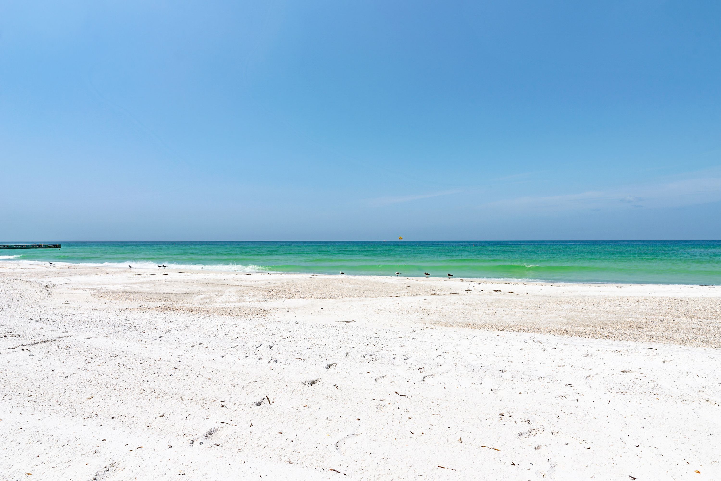 Ein Strand mit weißem Sand und klarem, blauem Wasser.