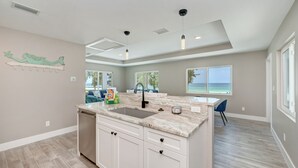 A modern kitchen with a large island, a built-in sink, and pendant lighting. - AMI Gulf Lookout-views Of The Gulf From Every Room-rooftop Terrace (Bradenton Beach)