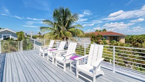 A wooden deck with white chairs and a palm tree. - AMI Gulf Lookout-views Of The Gulf From Every Room-rooftop Terrace (Bradenton Beach)