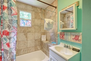 A bathroom with a bathtub, a sink, a shower, and a window. - AMI Lighthouse Cottage-one Minute Walk To The Beach-keyless Locks (Bradenton Beach)
