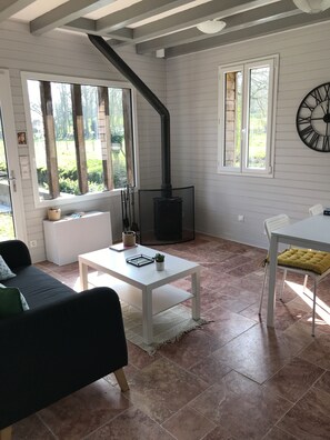 Un salon chaleureux avec une cheminée, un canapé, une table et un fauteuil.