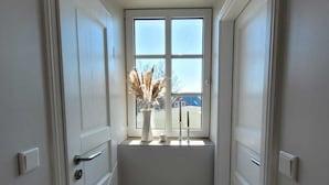 A narrow hallway with a window at the end, white doors, and a wooden floor. - Historic "Alter Bahnhof" Oberdorla with private playground, (Vogtei OT Oberdorla)